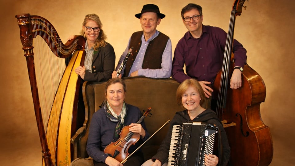 Ein Foto der fünf Musiker*innen mit ihren traditionellen Instrumenten vor gelb-braunem Hintergrund