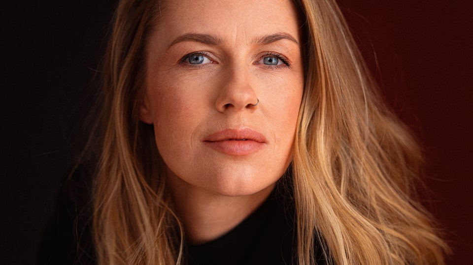 Portrait von Christine Eixenberger mit offenen Haaren in dunklem Pullover vor dunklem hintergrund
