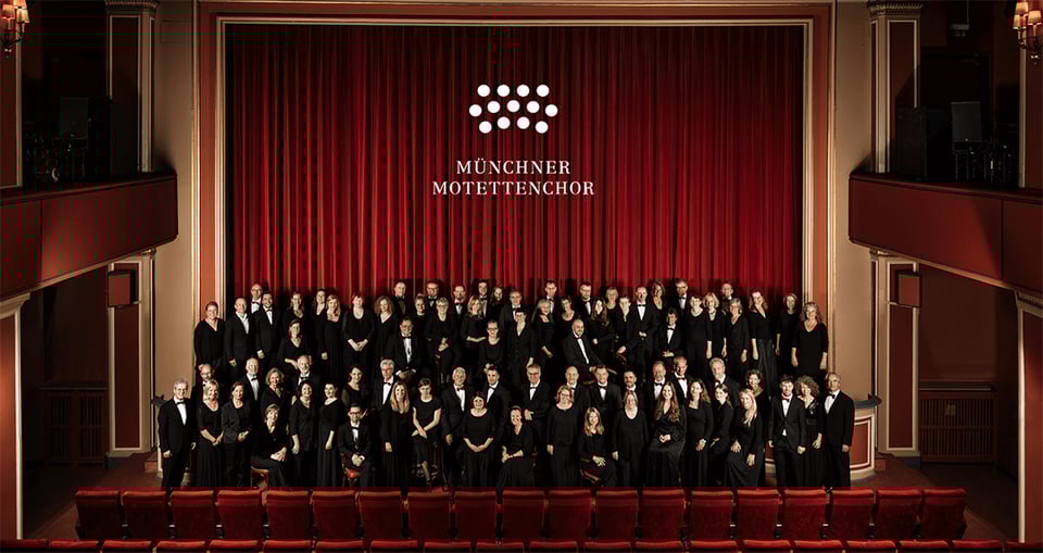 Der Münchner Motettenchor auf einer Bühne mit rotem Vorhang im Hintergrund