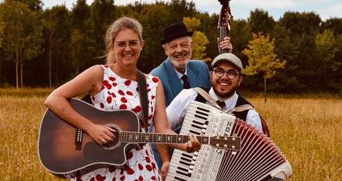 Drei Musiker*innen auf einem Feld mit Instrumenten in den Händen