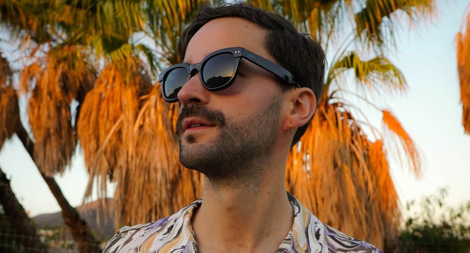 Mann mit Sonnenbrille unter Palme