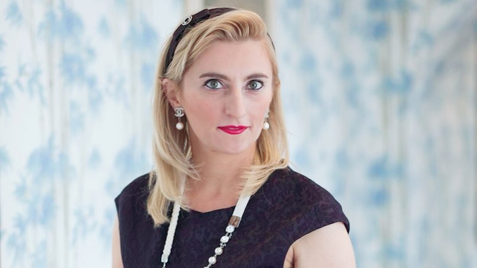 Porträtfoto zum Event „KLANGPERLEN – Klavierabend Catherine Gordeladze“: Eine Person ist vor einem hellen, blau‑weiß strukturierten Hintergrund dargestellt und trägt ein dunkles Oberteil sowie eine helle Halskette und Ohrringe. Die Aufnahme ist frontal, weich ausgeleuchtet und wirkt wie ein professionelles Künstlerporträt.