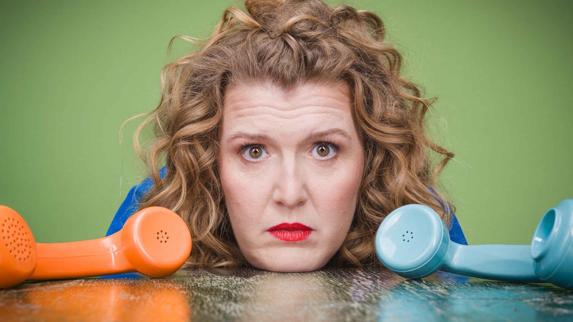 Die Künstlerin mit einem orangen und einem blauen Telefonhörer