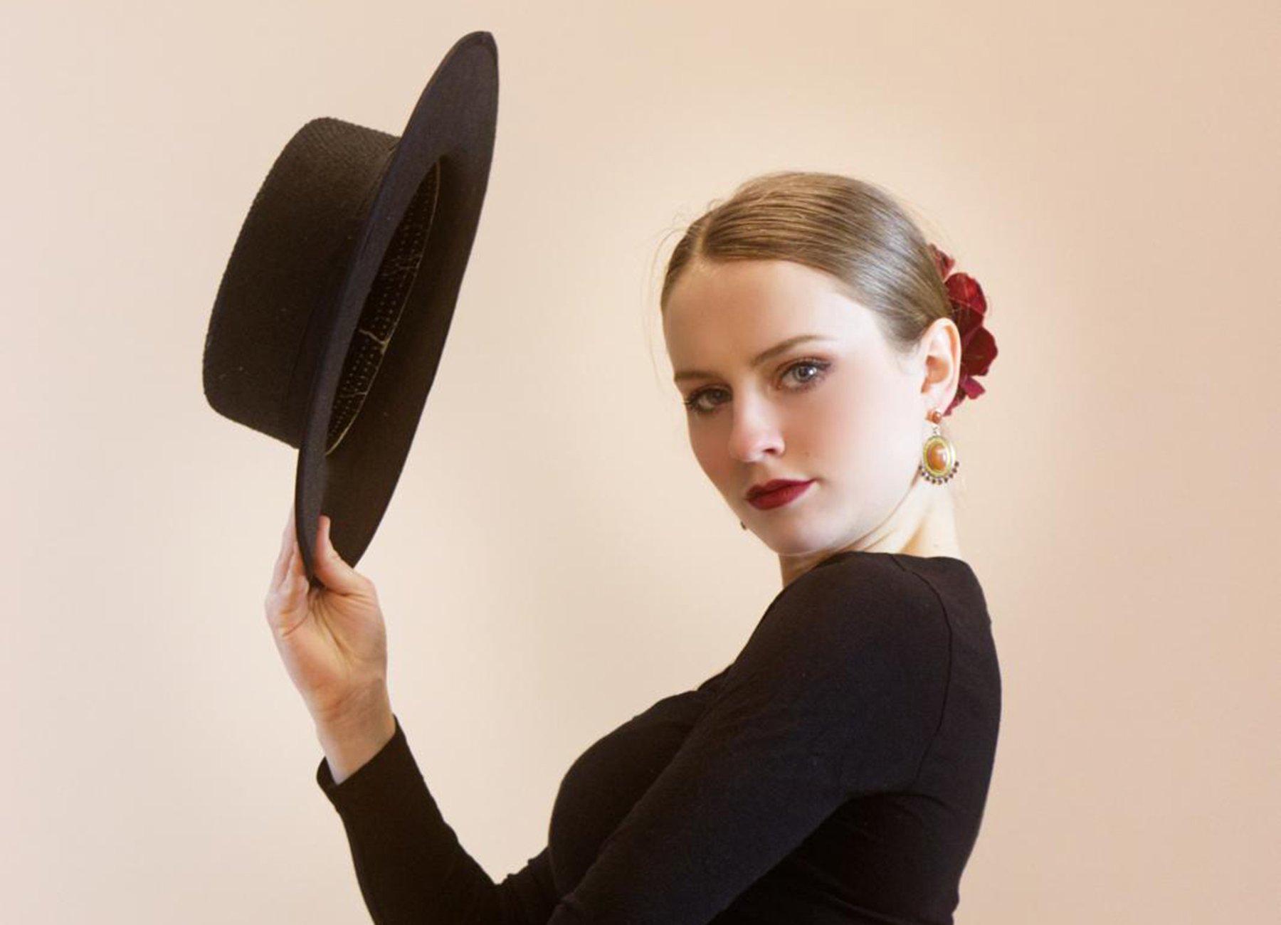 Foto eines Mädchens mit einem Flamenco-Hut vor einem hellbeigen Hintergrund