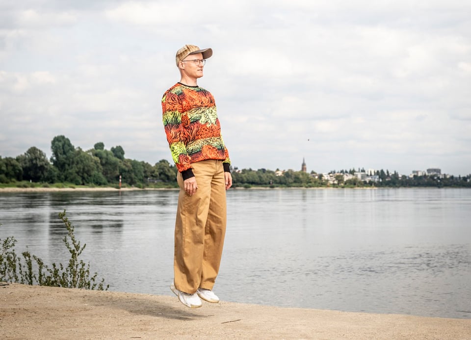 Foto eines Mannes, der schwebt, ohne den Boden zu berühren, mit einem See im Hintergrund.