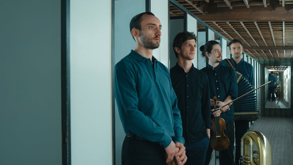 Foto für das Event „Maxjoseph – Albumpräsentation Lagom“ mit den Künstlern mit ihren Instrumenten in einem Flur mit Türen und einem Spiegel am Ende.