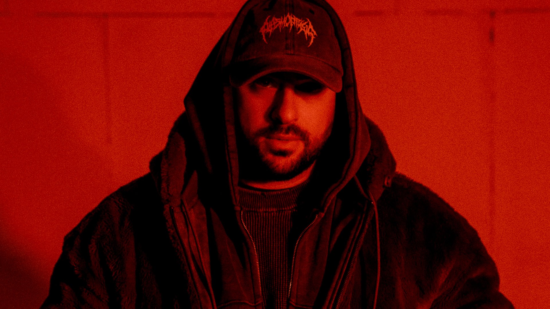 Portrait in schwarz/rot des Künstlers Timey mit Kapppe und dunkler Kleidung sowie Kapuze