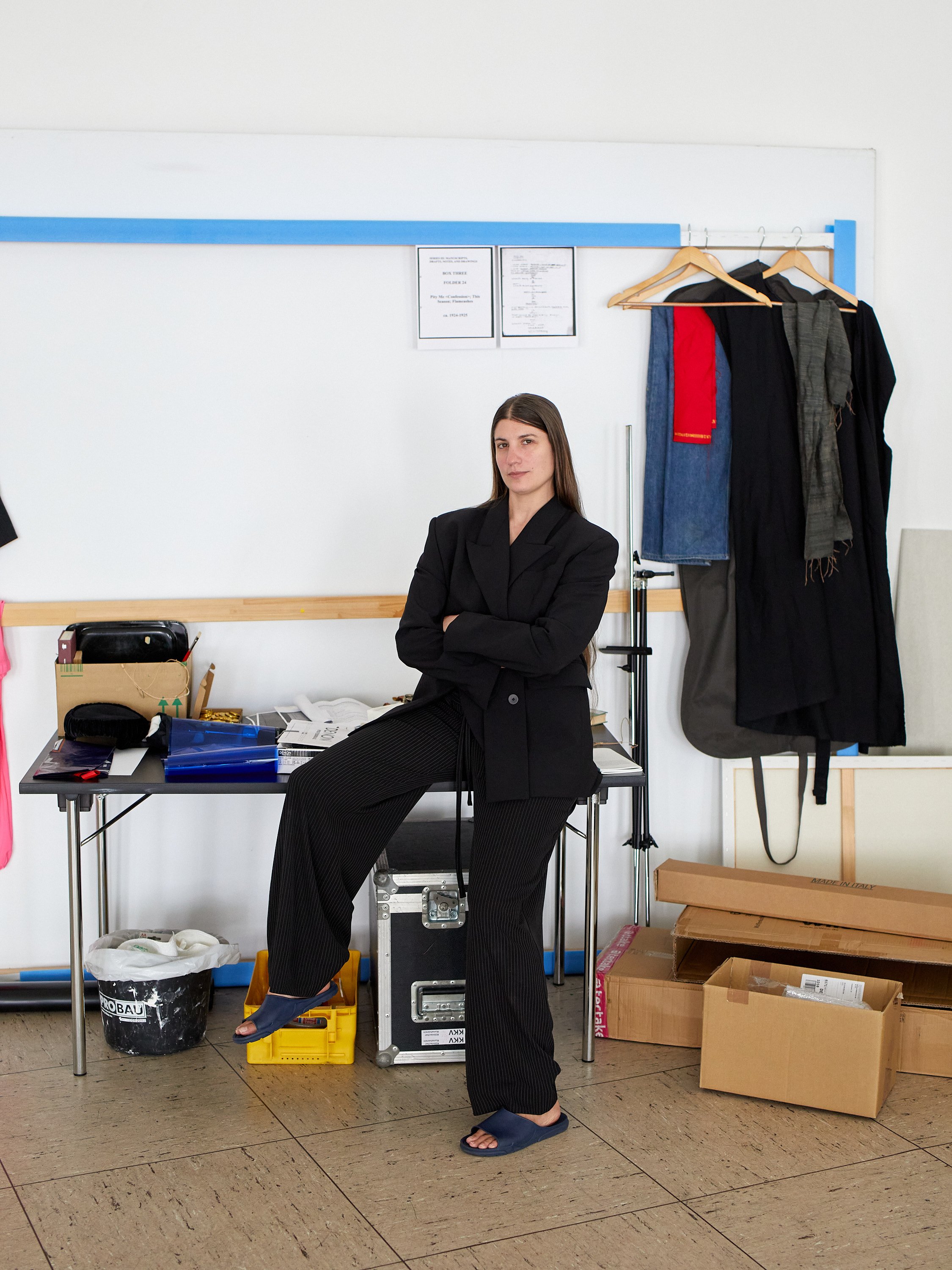 Foto einer Frau, die an einem Tisch sitzt und die Arme verschränkt