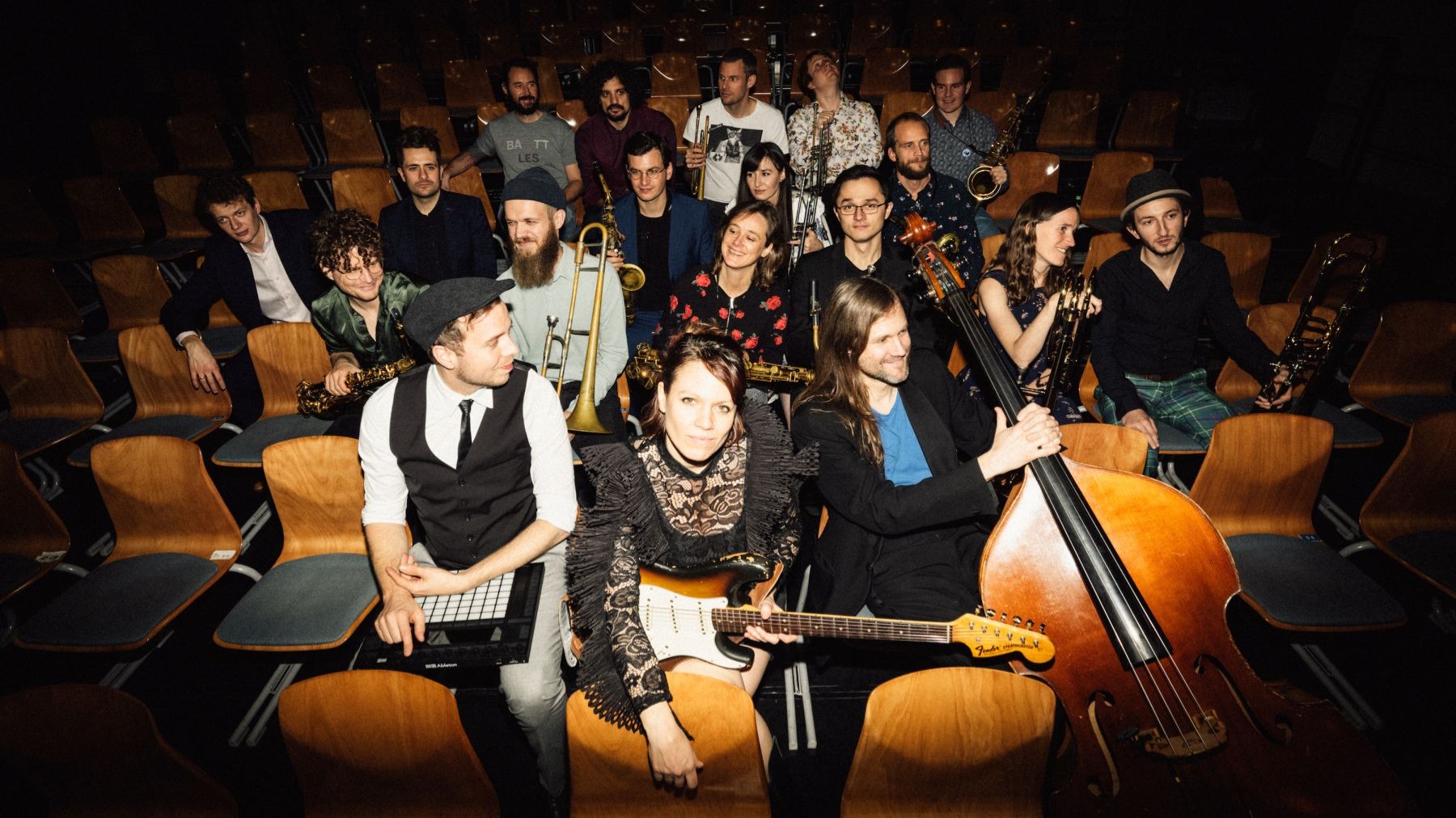 Die Monika Roscher Bigband mit Instrumenten posiert in einem Zuschauersaal