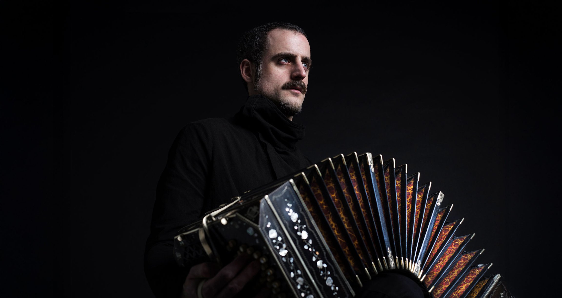 Künstler mit Bandoneon vor schwarzem Hintergrund