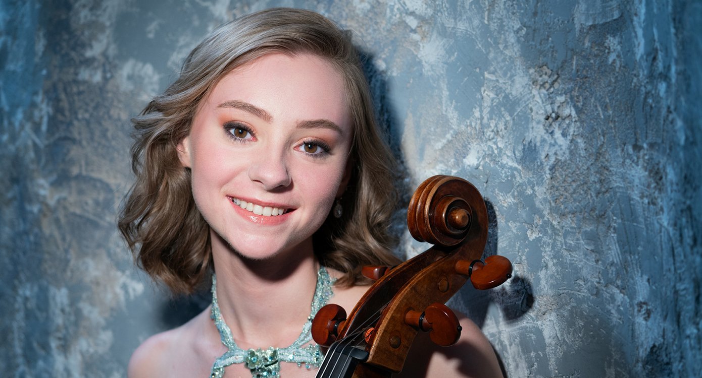 Foto von Luka Coetzee mit einem Instrument und einer blauen Steinkette, vor einer blauen Wand
