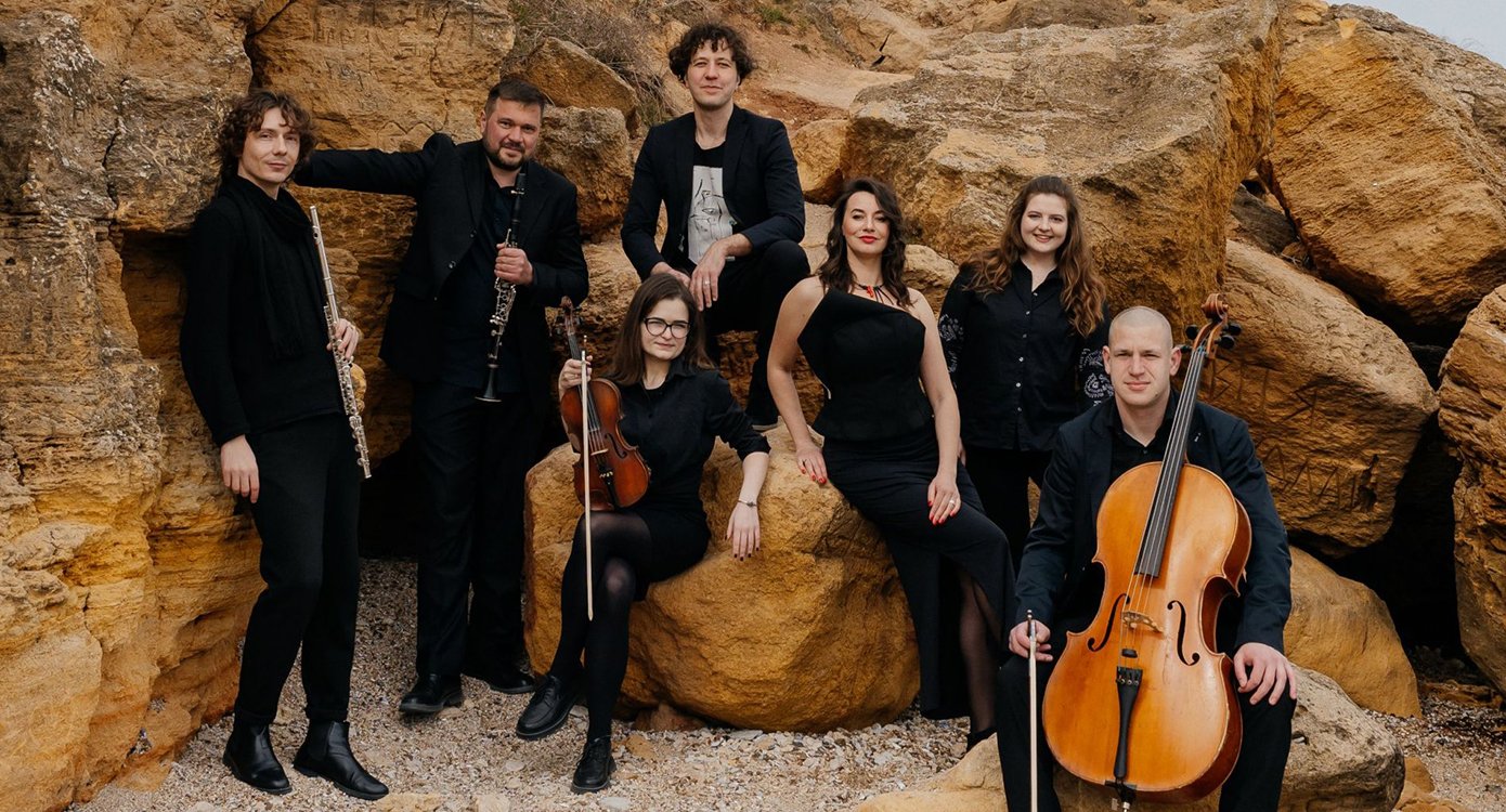 Foto der Musikgruppe „ensemble senza sforzando“, alle in schwarz gekleidet, mit Instrumenten und im Hintergrund einige Steine.