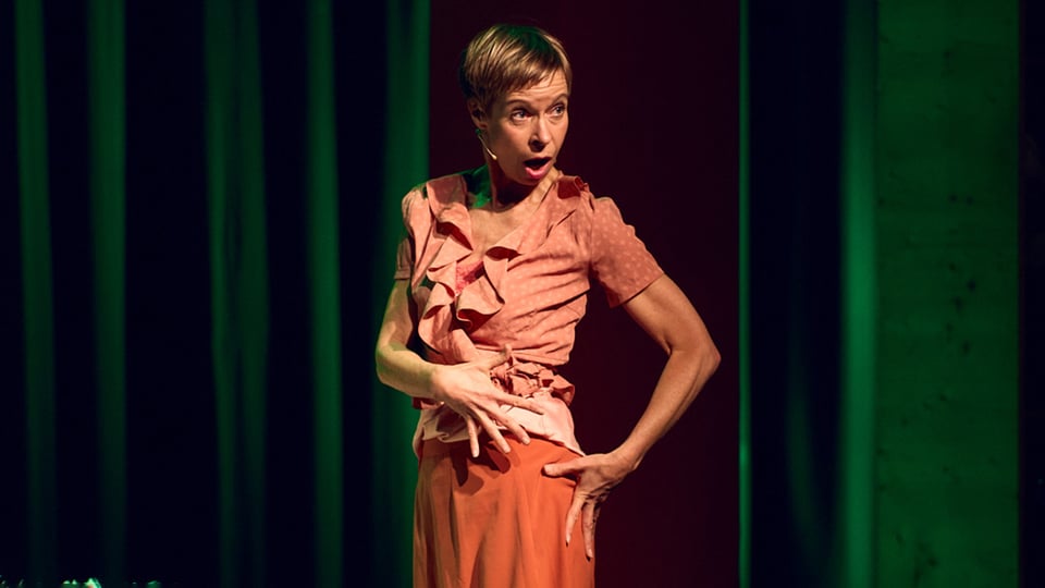 Foto für die Veranstaltung CAVEWOMAN mit der Künstlerin Ramona Kronke und mit einem grünen Vorhang im Hintergrund.