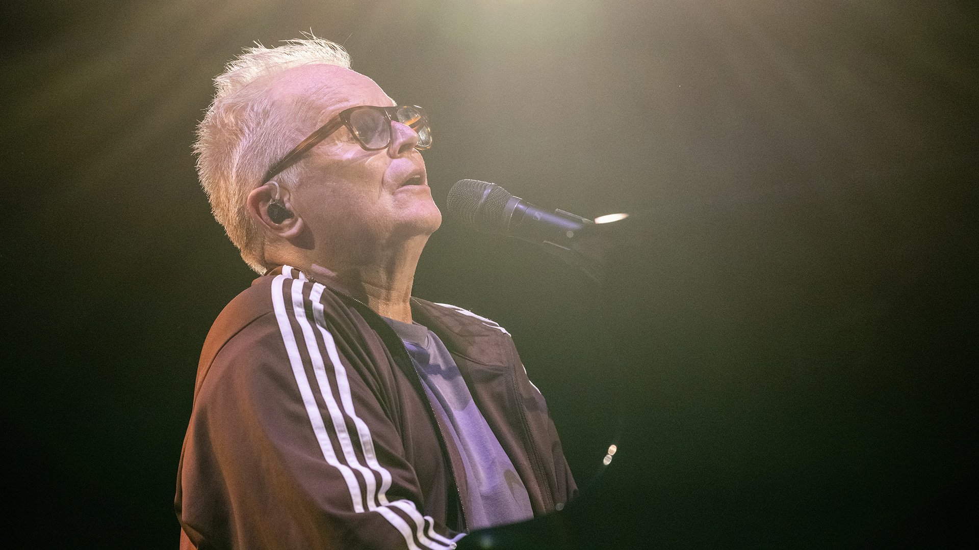 Foto von Herbert Grönemeyer mit einem Mikrofon und einer Brille.