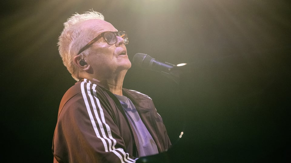 Foto von Herbert Grönemeyer mit einem Mikrofon und einer Brille.