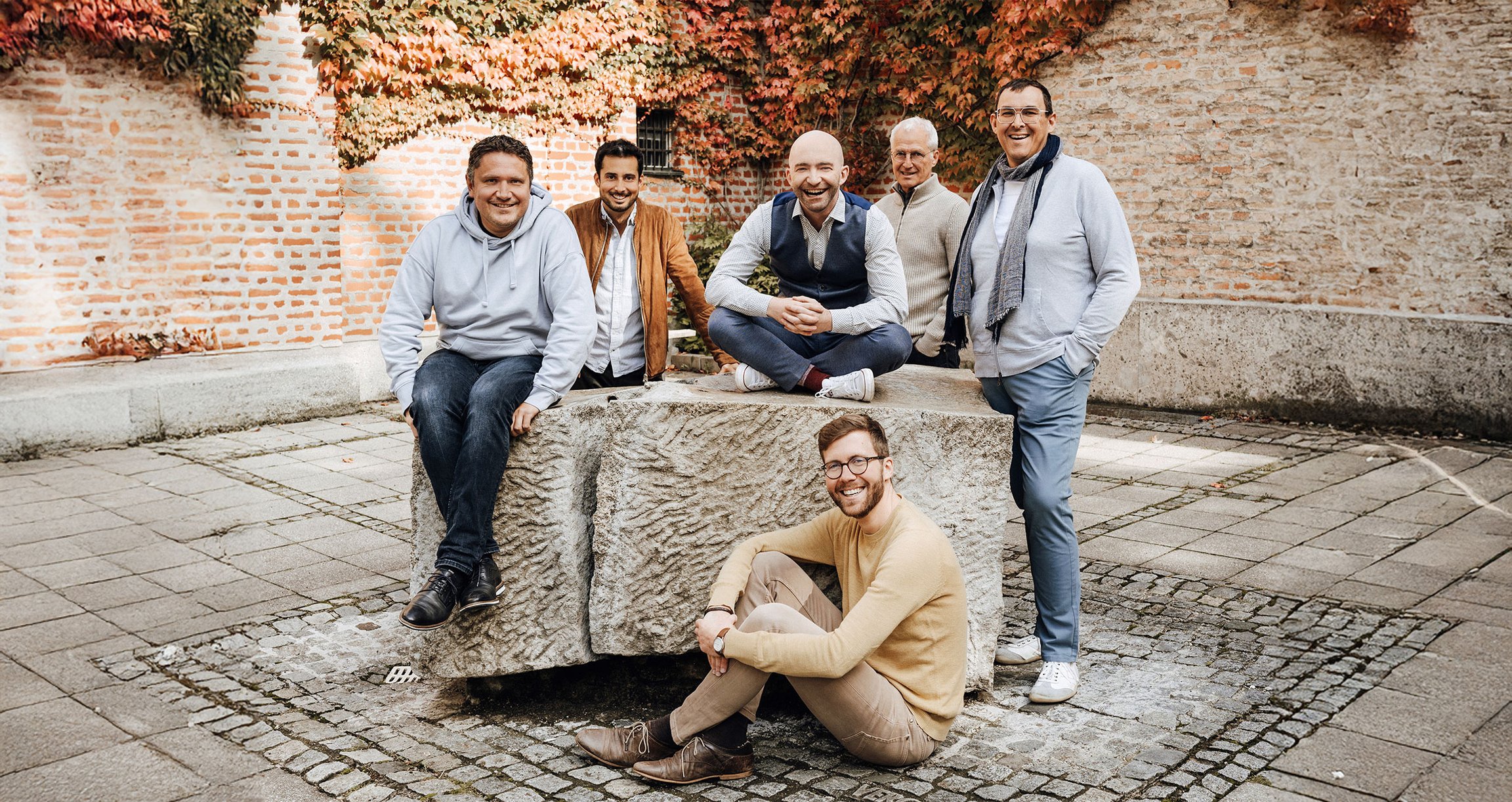 Sechs Männer in Freizeitkleidung in Innenhof