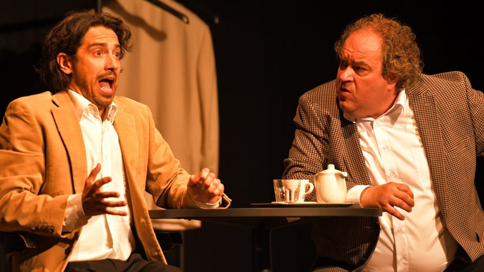 Zwei Männer sitzen an einem Tisch und reden miteinander