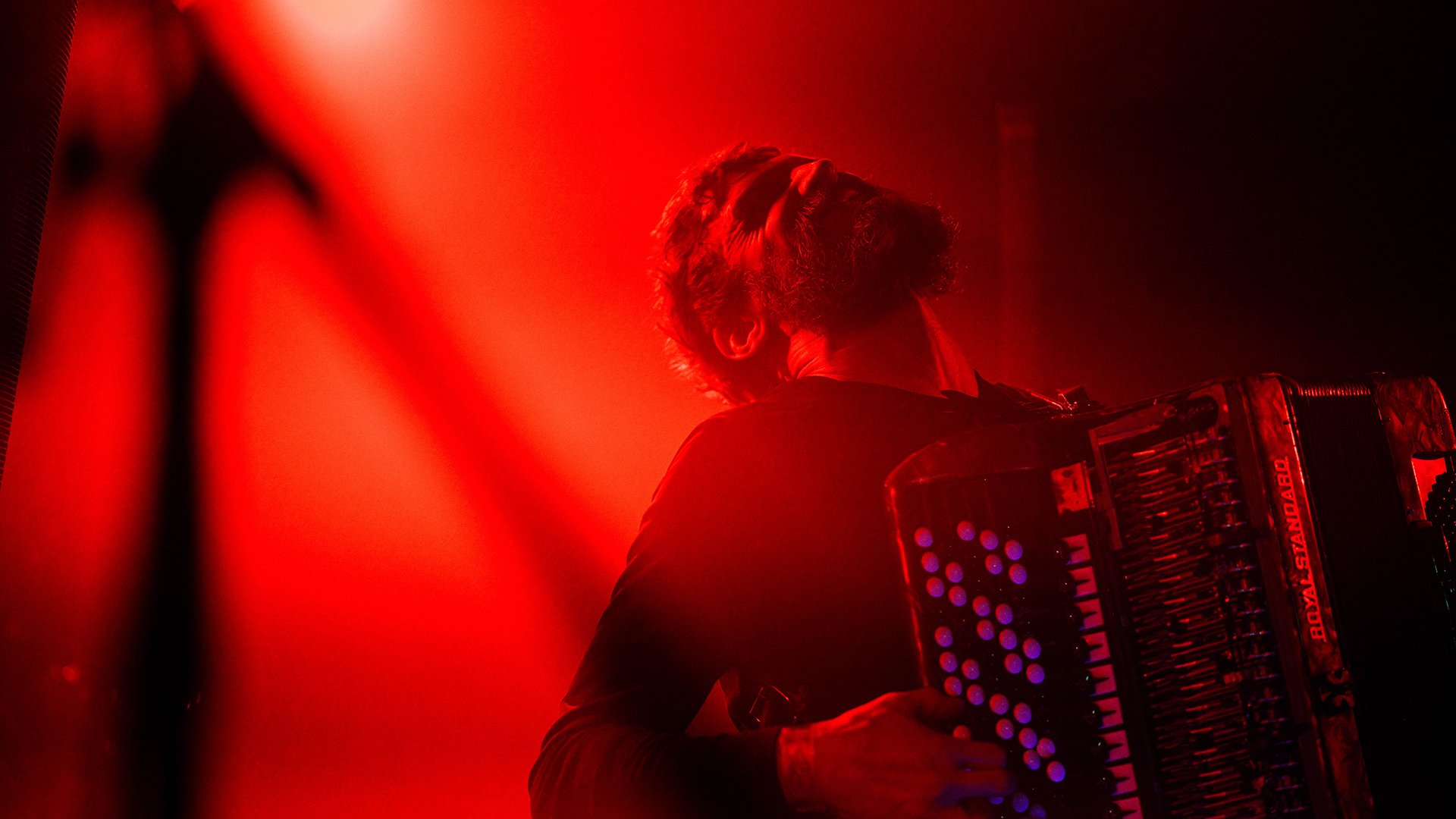 Der Künstler mit Akkordeon auf der Bühne in rotem Scheinwerferlicht