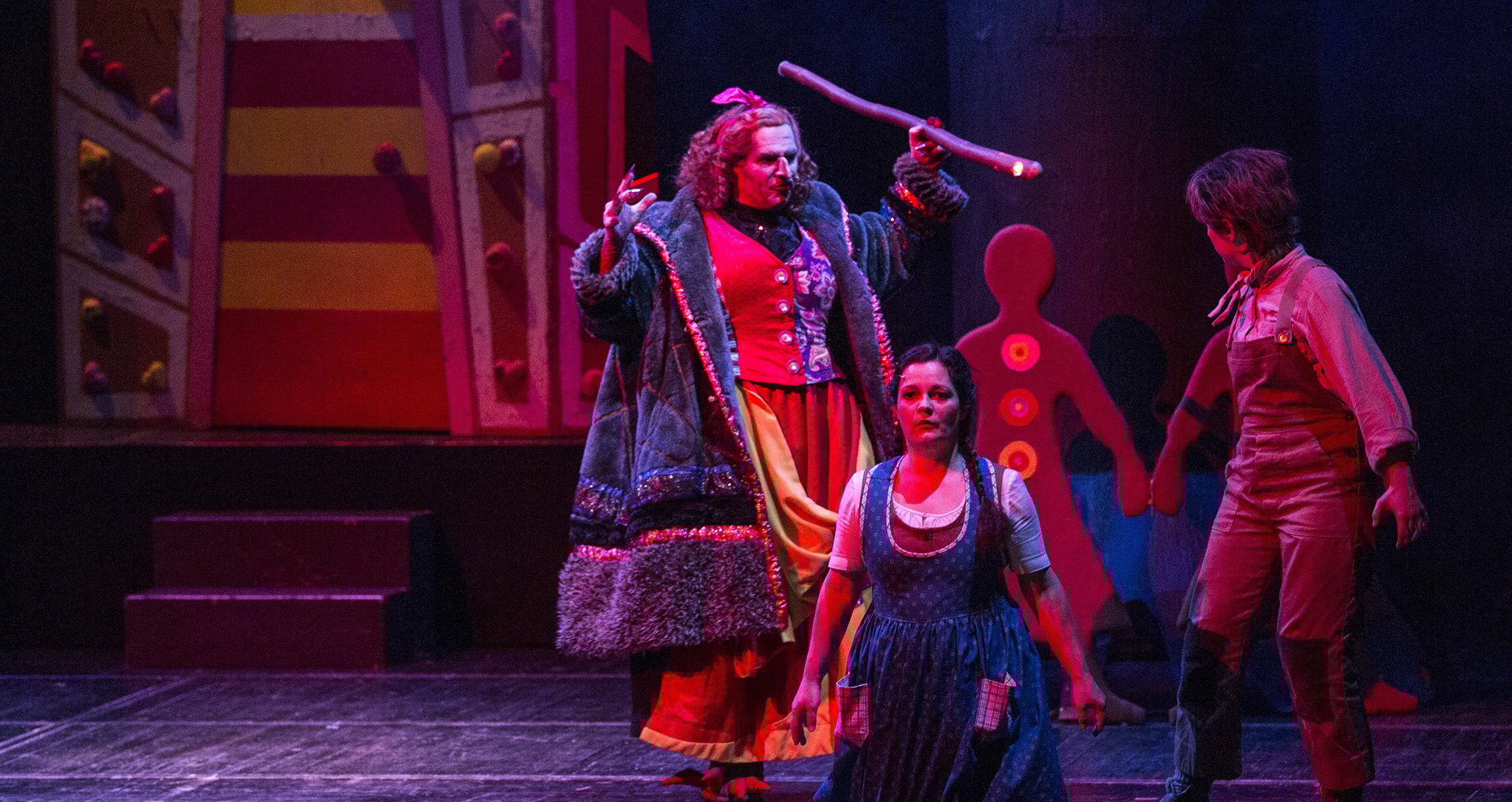 ein Bild des Theaterstücks mit drei Darstellern und dem Bühnenbild