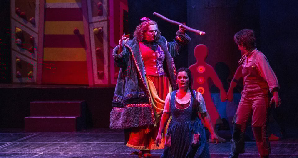 ein Bild des Theaterstücks mit drei Darstellern und dem Bühnenbild