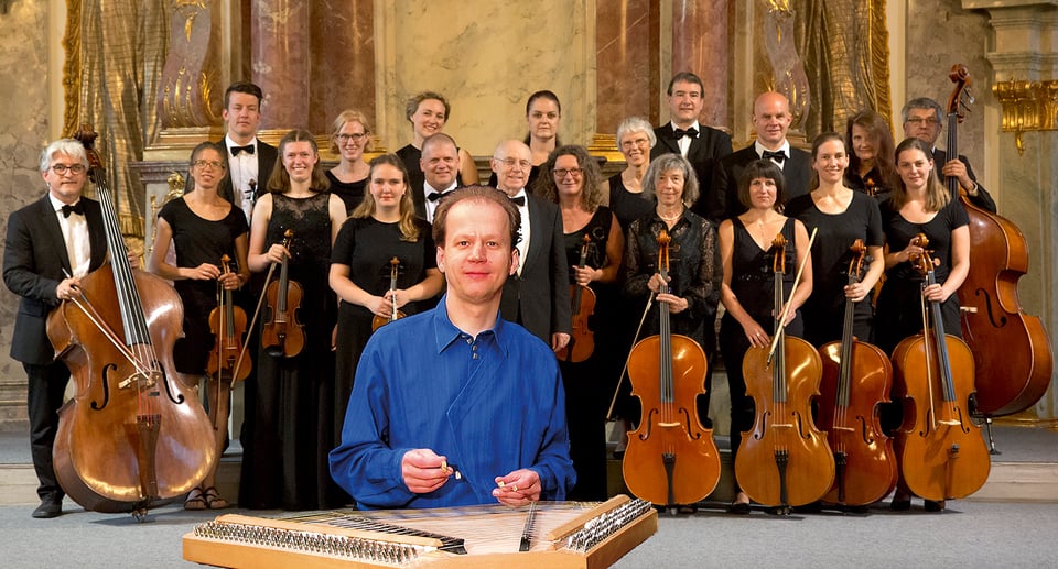 Mitglieder des Kammerorchesters mit Instrumenten sowie Künstler vorne im Bild