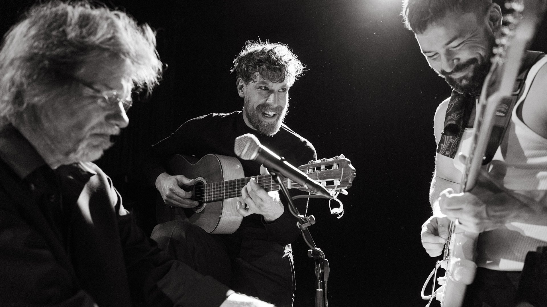 Ein schwarz-weiss Foto von drei Musikern der Veranstaltung People Are Strange mit zwei Gitarren und Mikrofon