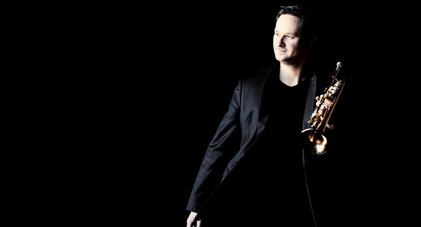 Foto des Künstlers „Gábor Boldoczki“, mit schwarzem Hintergrund und einem Instrument in seiner Hand