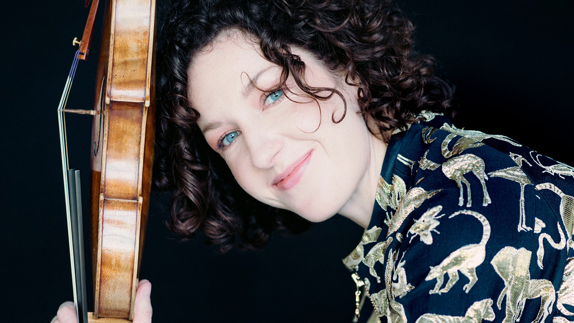 Portrait einer Dame in gemusterter Bluse mit Instrument vor dunklem Hintergrund