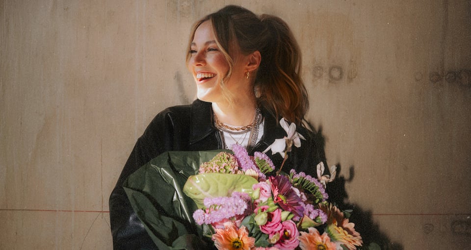 Sophia lacht und hält einen Blumenstrauß