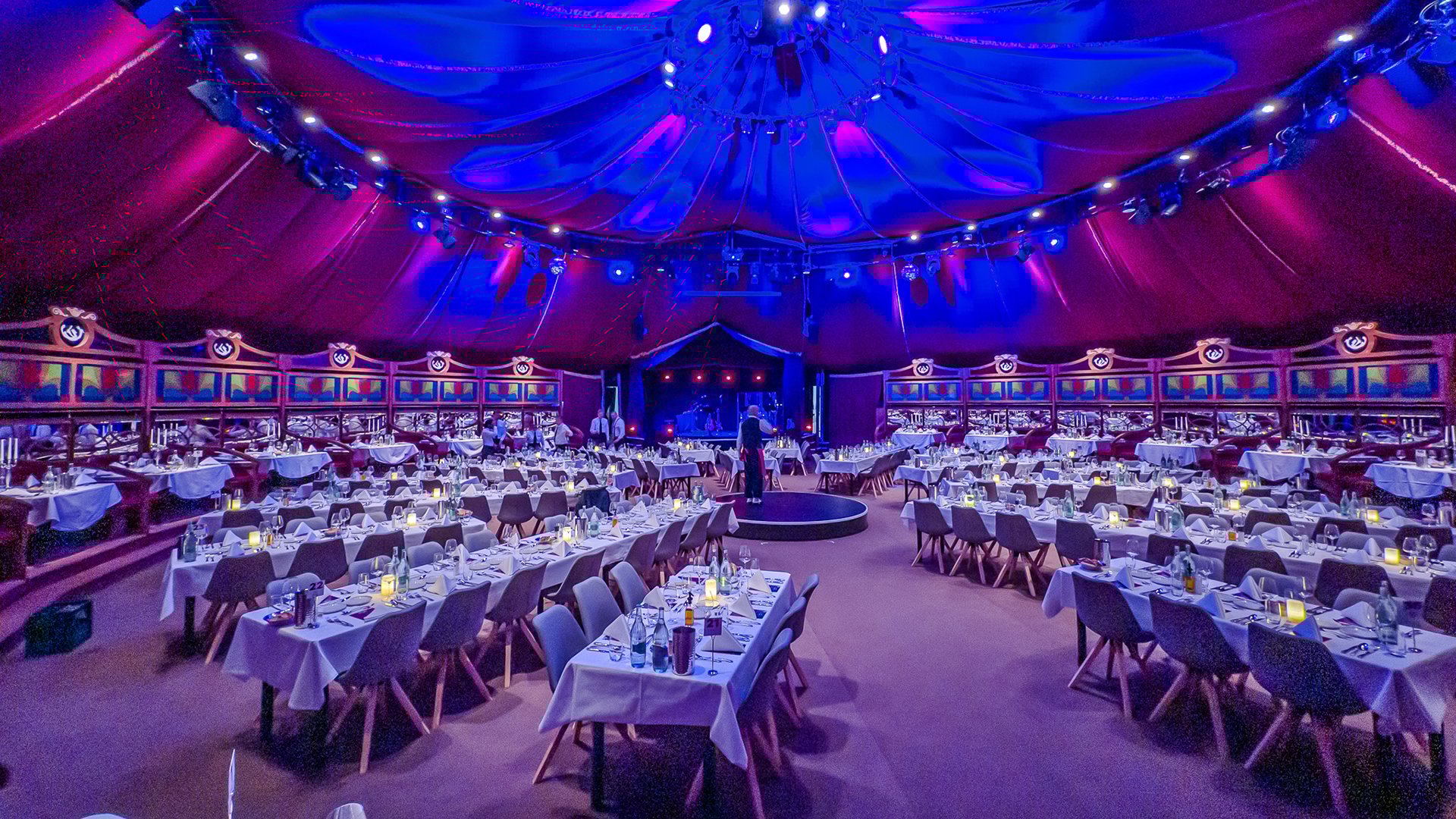Das Zelt mit festlich gedeckten Tischen in blauem Scheinwerferlicht