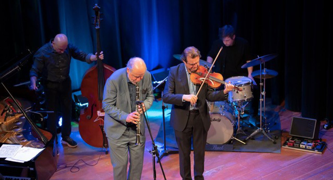Vier Musiker mit Instrumenten auf einer Bühne