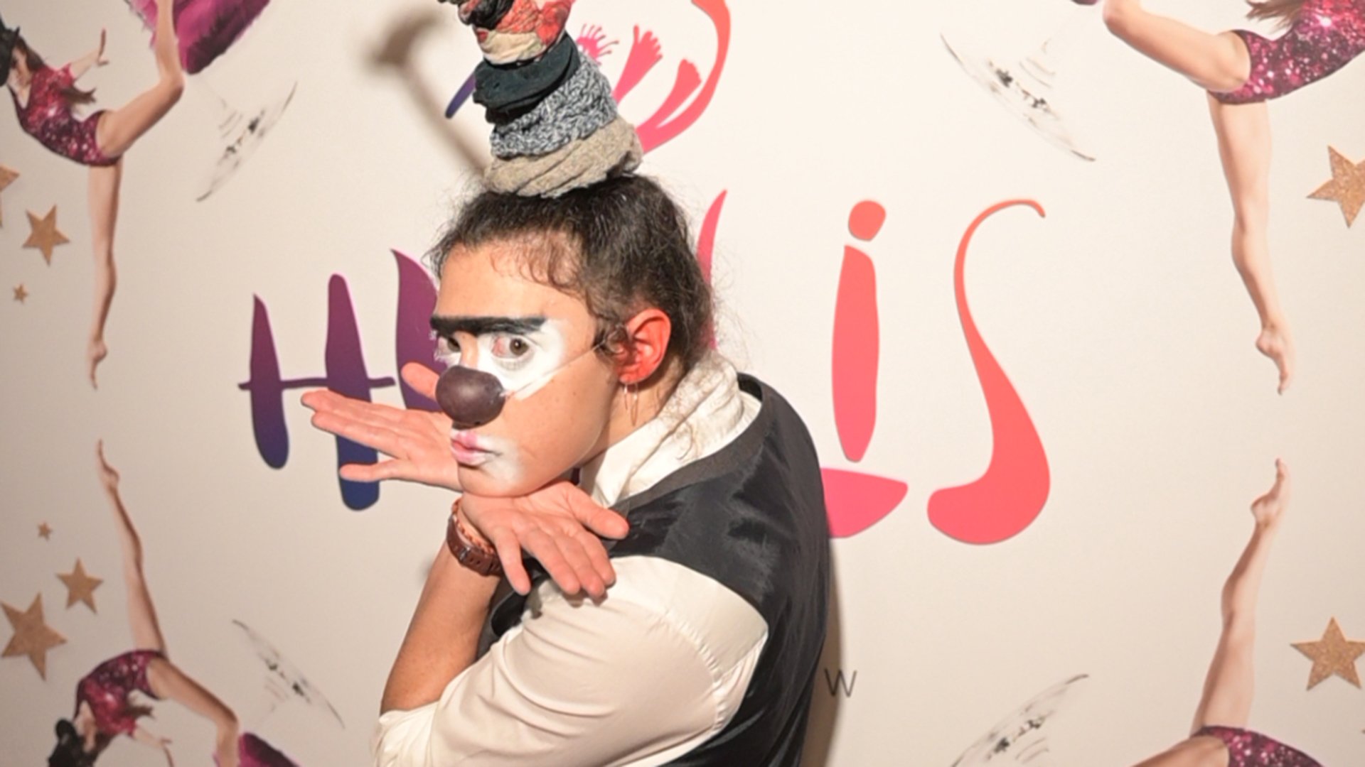 Ein Darsteller mit Kopfschmuck vor einem Hulllis Plakat