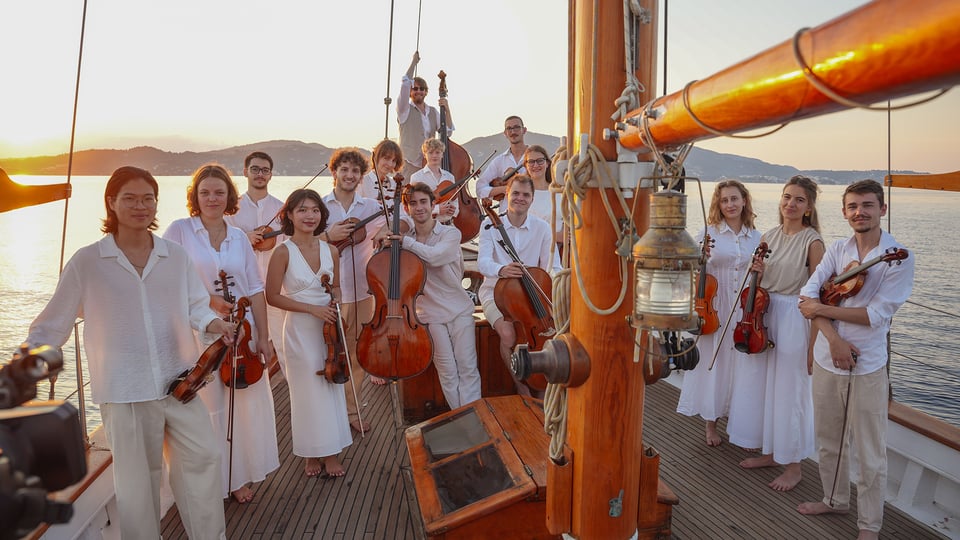 Foto für die Veranstaltung Strings in Motion – "Klangwelten": Mendelssohn-Bartholdy, Weber, Tschaikowsky, Rotas mit der gesamten Gruppe auf einem Boot mit Instrumenten.