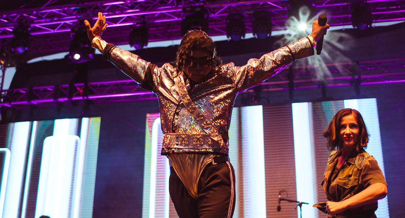 Auf der Bühne steht ein Mann im Michael-Jackson-Outfit, neben ihm auf der linken Seite steht eine Frau