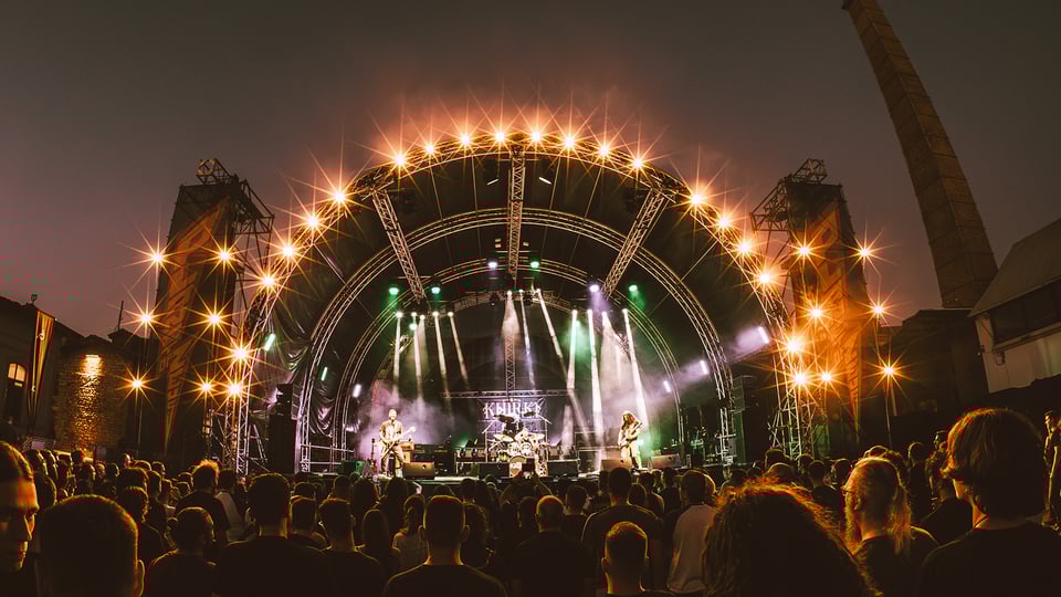 Band auf einer Bühne mit Scheinwerferlicht und Publikum