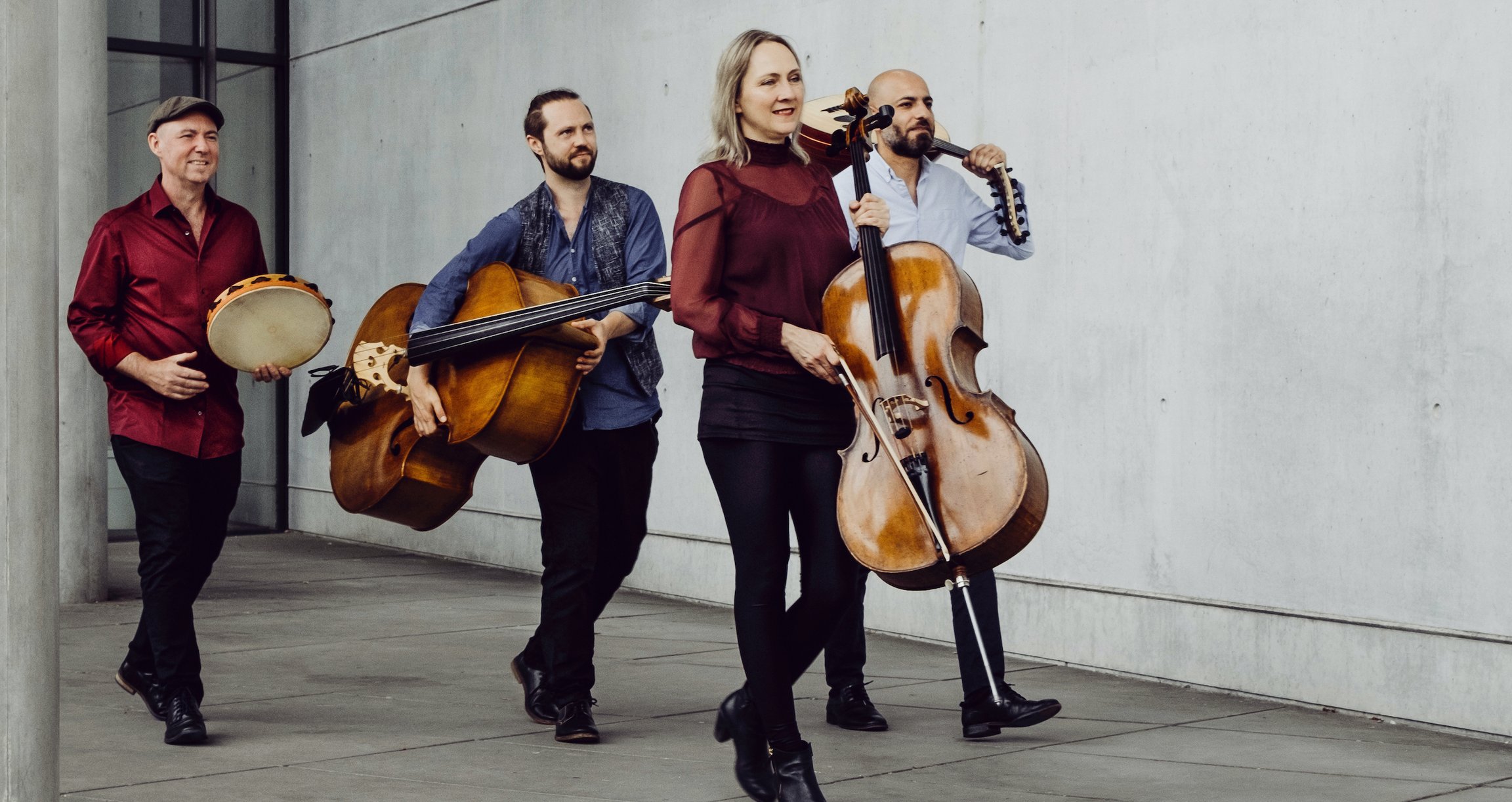 Vier Personen, die mit klassischen Instrumenten vorbeilaufen
