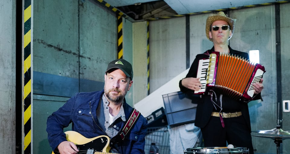 Zwei Männer in Halle mit Gitarre und Zieharmonika