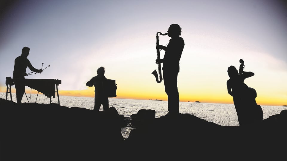 Foto für das Event Quadro Nuevo – Inside the Island: mit der Gruppe, die mit ihren Instrumenten spielt, und dem Meer im Hintergrund