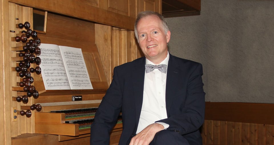 Mann in Anzug vor einer hölzernen Orgel