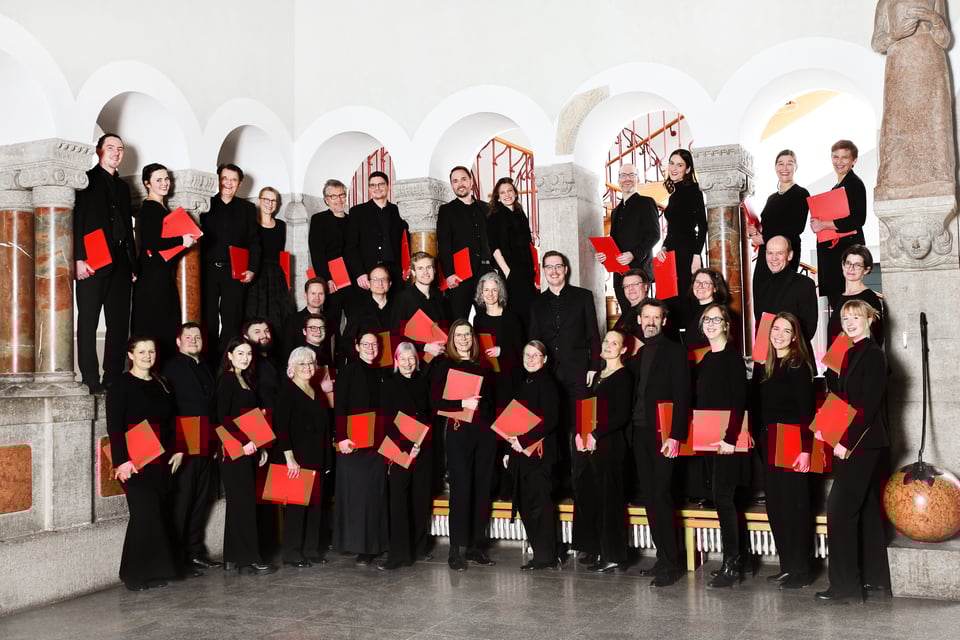 Foto für die Veranstaltung SINGET! mit dem Chor, alle in schwarzer Kleidung und mit einer roten Mappe