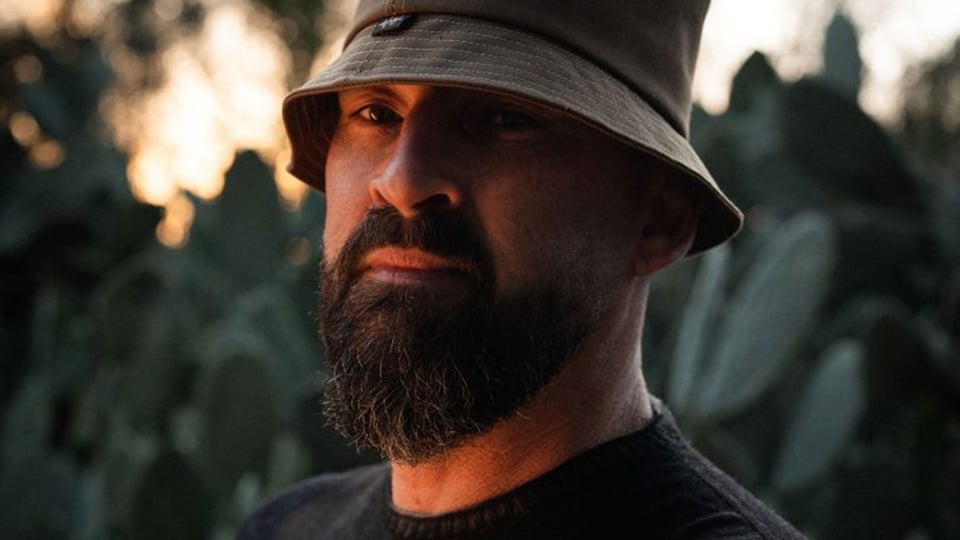 Porträt des Reggae-Künstlers Gentleman mit Bart und Hut im Freien bei warmem Licht, Nahaufnahme vor unscharfem Hintergrund, Pressefoto zur Konzerttour.