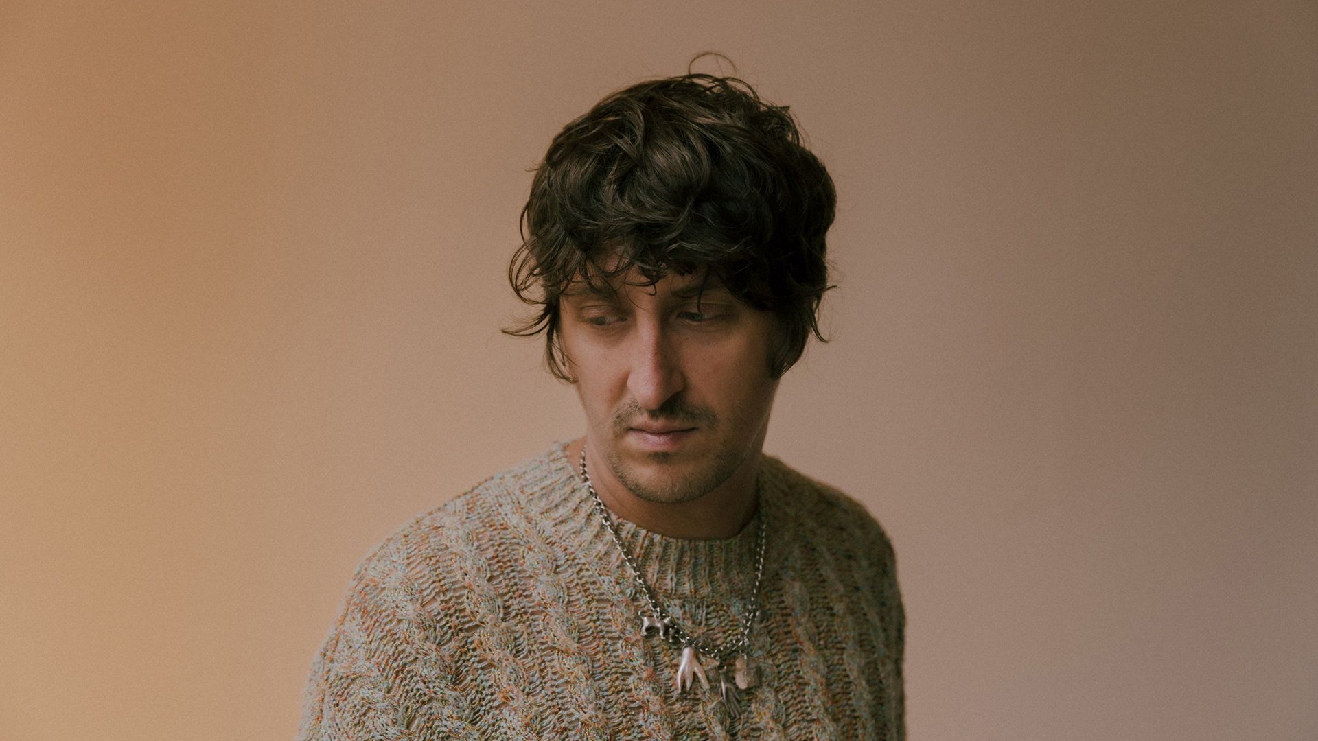 Ein Portrait des Künstlers in einem beigen Strickpullover