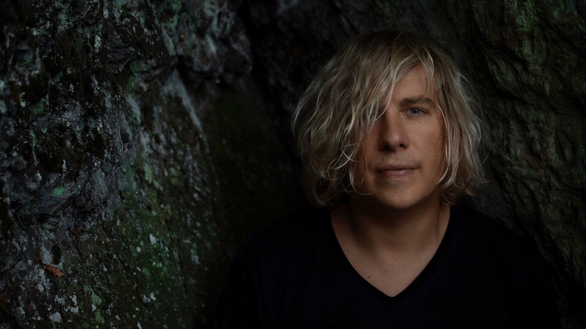 Foto für das Event von Dominik Eulberg, mit einem Bild des Künstlers vor einer Fels- bzw. steinartigen Textur im Hintergrund