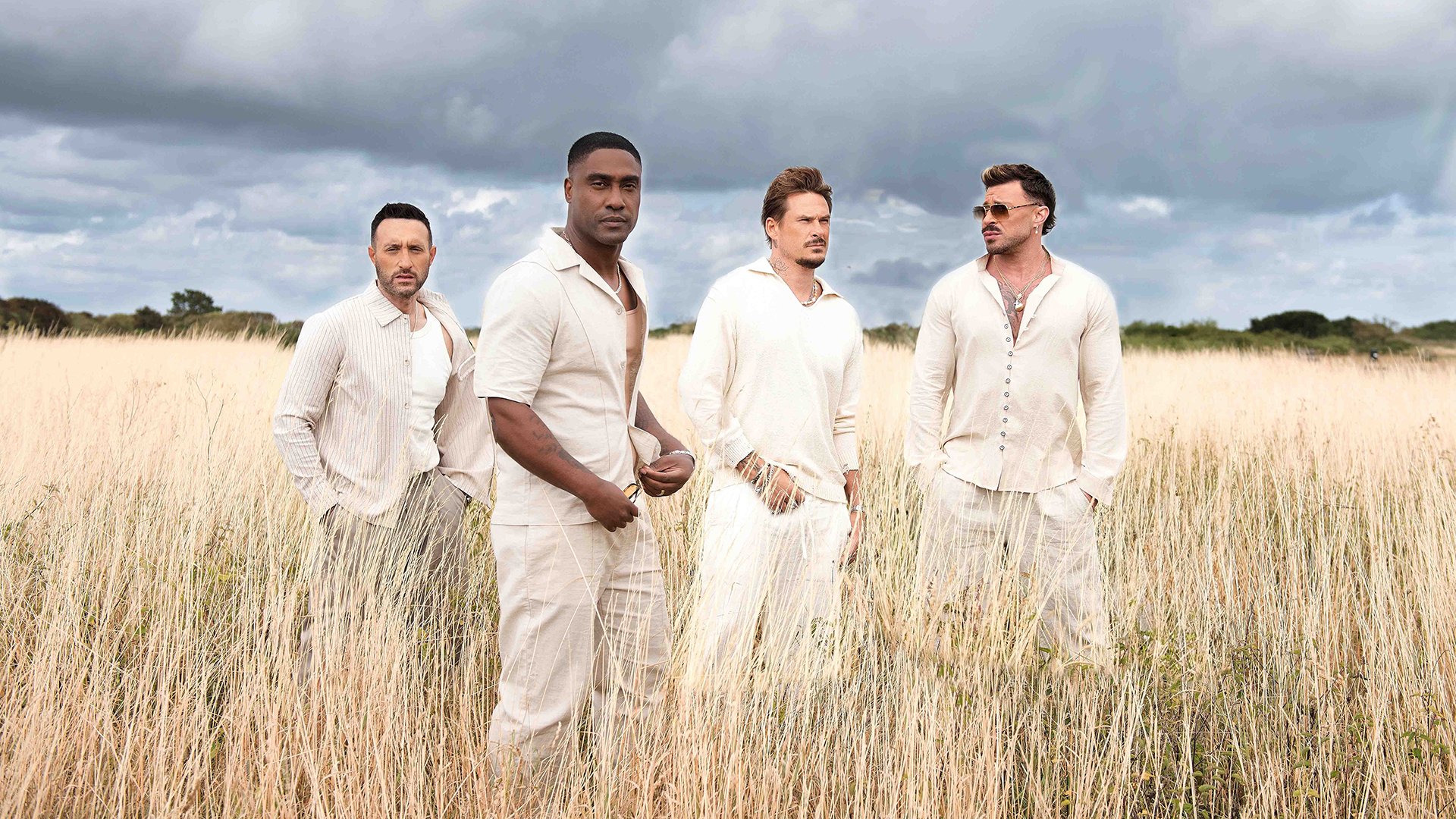 Vier hell gekleidete Männer stehen in einem Kornfeld