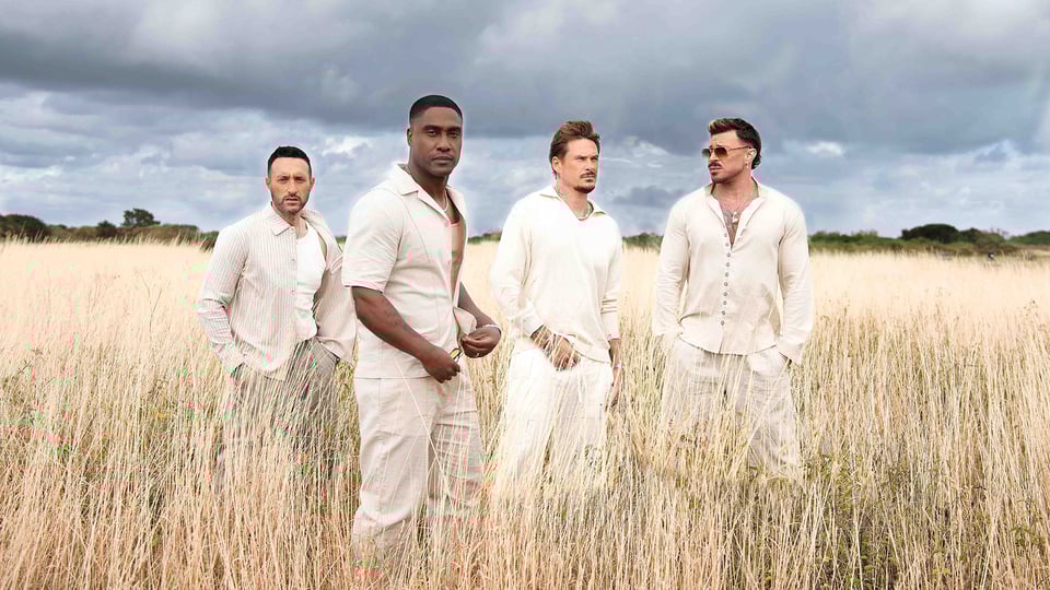 Vier hell gekleidete Männer stehen in einem Kornfeld
