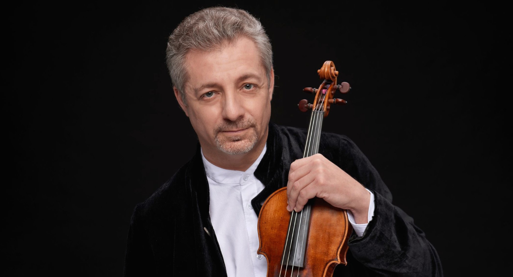 Foto des Künstlers mit Instrument vor schwarzem Hintergrund