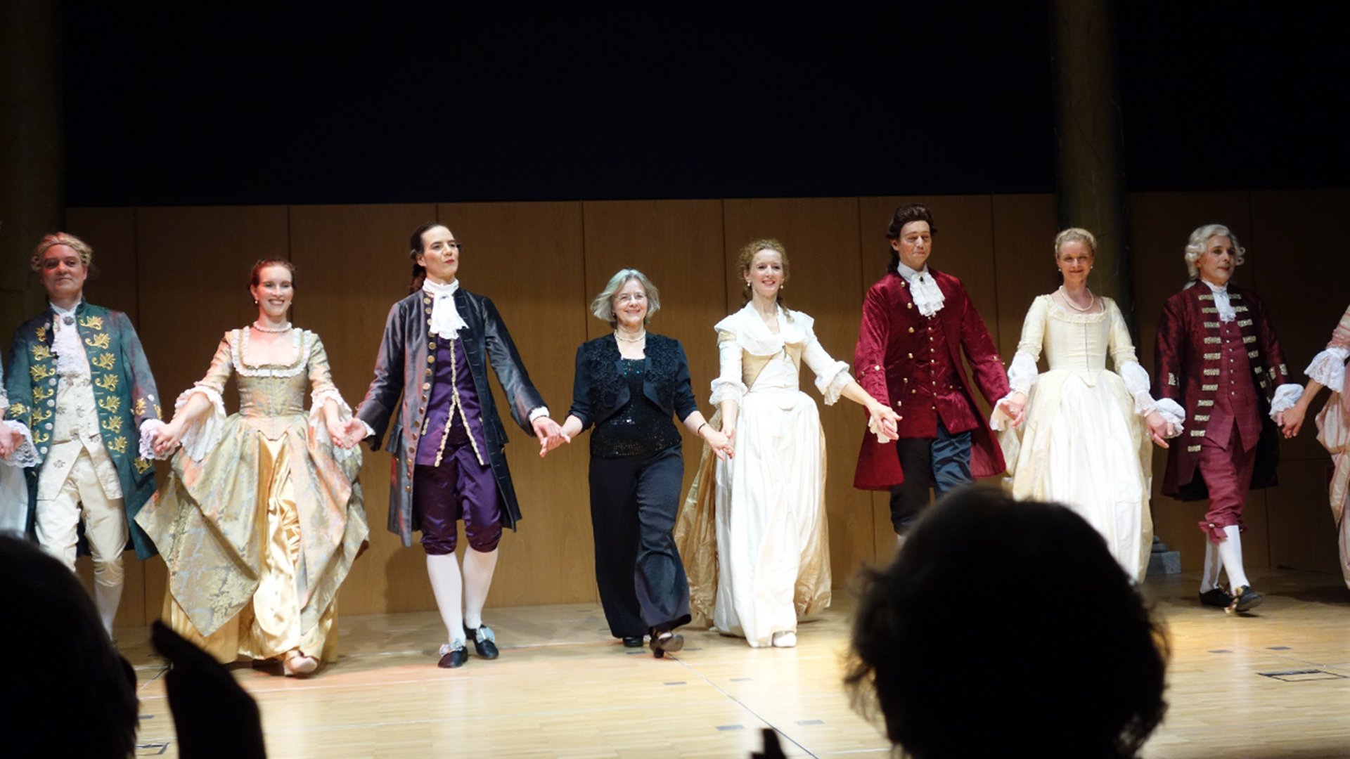 Acht Personen auf einer Bühne in Kostümen