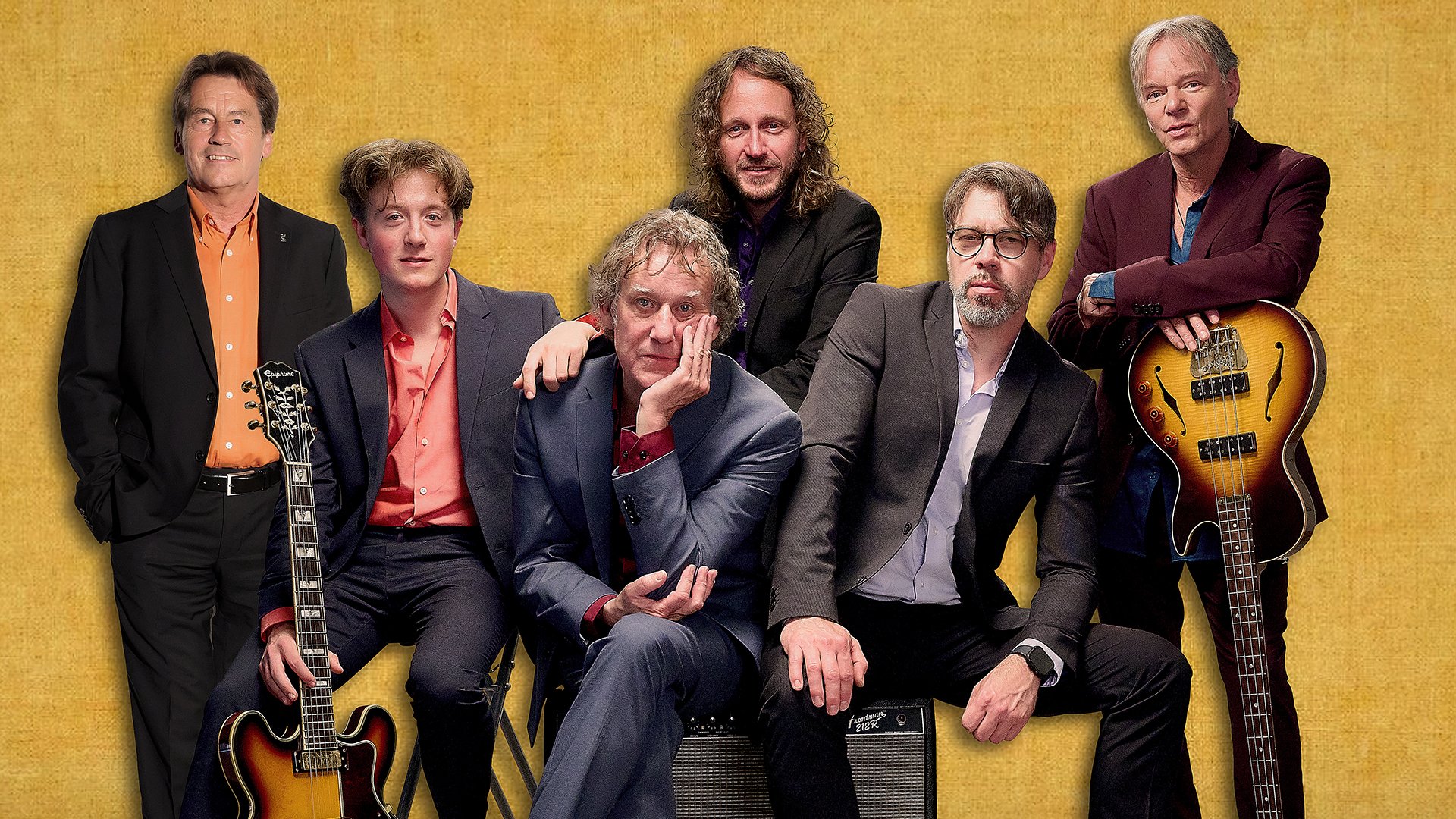 Sechs Mitglieder der Band Pepperland in dunklen Anzügen mit Instrumenten vor gelbem Hintergrund