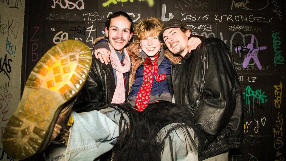 Foto für das Event Fruchtiger Beigeschmack – Tourabschluss 2026: die drei Künstler vor einer Wand mit Graffiti und Bemalungen.