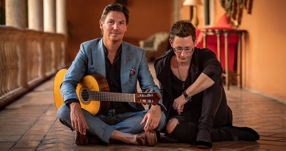 Die Musiker sitzen gemeinsam am Boden mit Gitarre